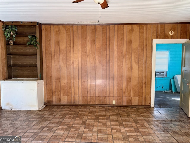 empty room with cooling unit, ceiling fan, and wood walls