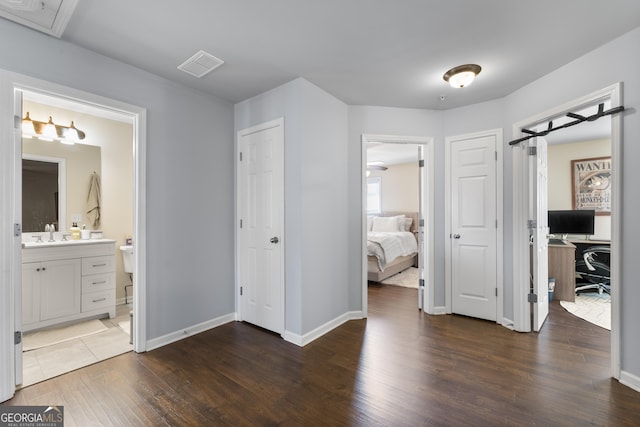 bedroom with dark wood-type flooring, connected bathroom, and sink