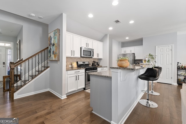 kitchen with a kitchen island with sink, white cabinetry, a breakfast bar, and appliances with stainless steel finishes