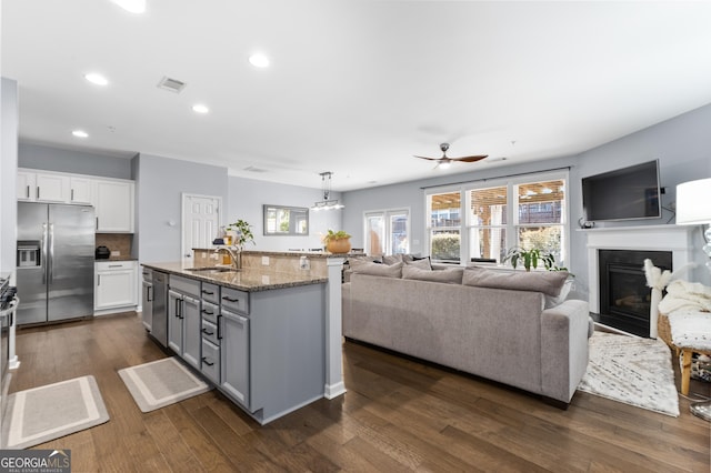 kitchen featuring sink, white cabinetry, an island with sink, stainless steel appliances, and light stone countertops