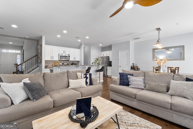 living room featuring ceiling fan and dark hardwood / wood-style flooring