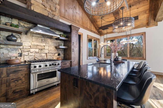 kitchen featuring pendant lighting, sink, high end range, a center island with sink, and wall chimney range hood