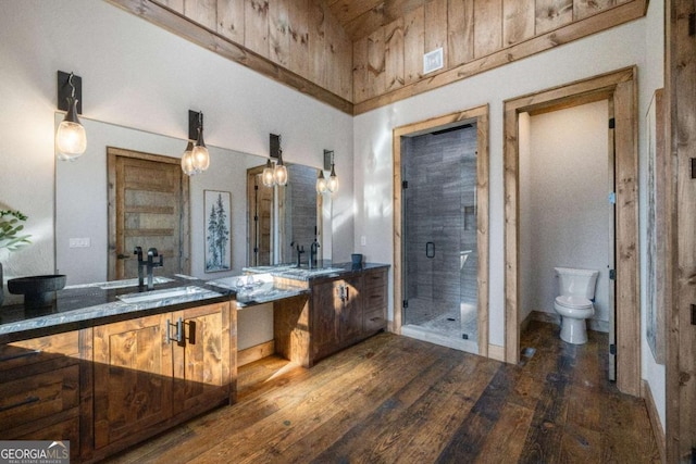 bathroom featuring toilet, a shower with shower door, wood-type flooring, vanity, and a towering ceiling