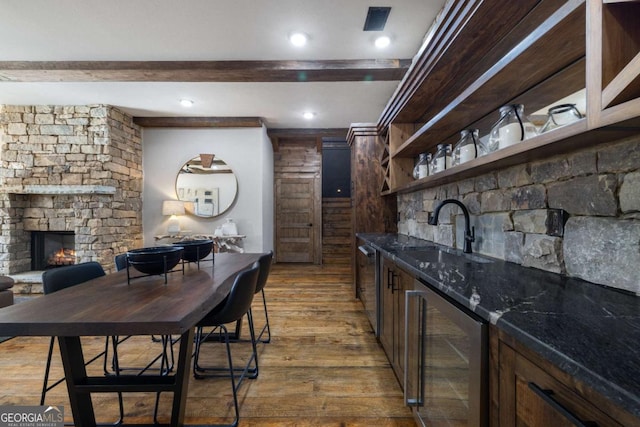 bar with hardwood / wood-style floors, a fireplace, sink, beverage cooler, and beam ceiling