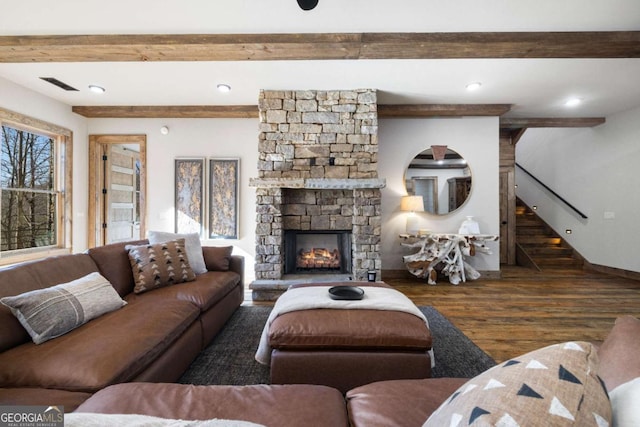 living room with dark hardwood / wood-style flooring, a stone fireplace, and beamed ceiling