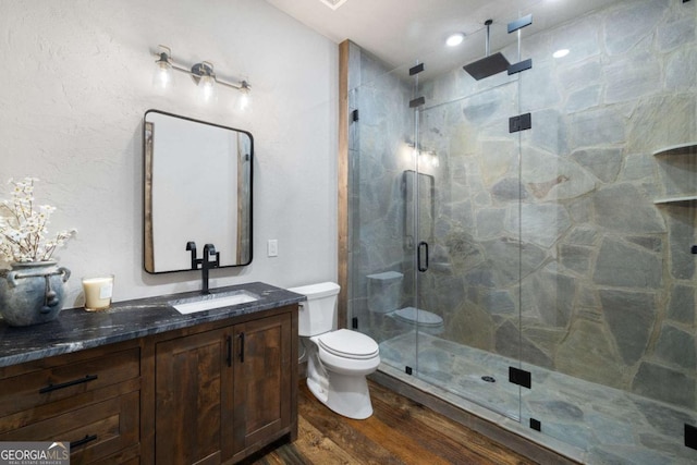 bathroom featuring vanity, hardwood / wood-style floors, a shower with shower door, and toilet