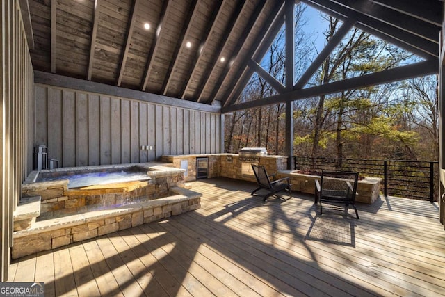 deck with a grill, a hot tub, exterior kitchen, and a fire pit