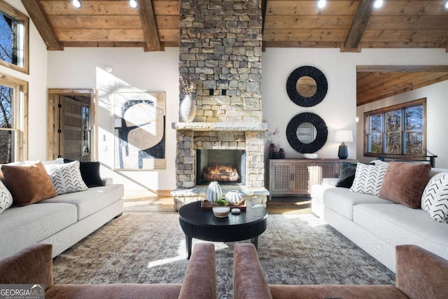 living room with high vaulted ceiling, a stone fireplace, wooden ceiling, and beamed ceiling