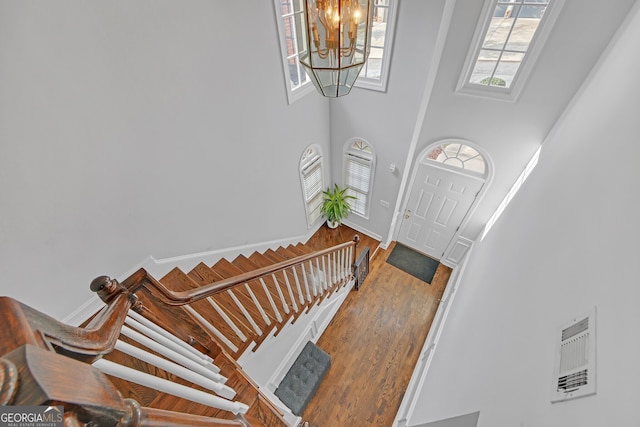 entrance foyer featuring a towering ceiling, hardwood / wood-style floors, and an inviting chandelier