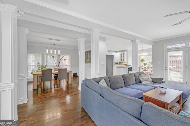 living room with dark hardwood / wood-style flooring, ornamental molding, decorative columns, and a chandelier