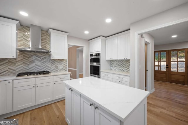 kitchen with white cabinets, stainless steel appliances, and wall chimney exhaust hood