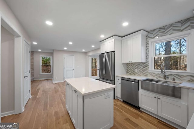 kitchen featuring sink, stainless steel appliances, light hardwood / wood-style floors, white cabinets, and a kitchen island