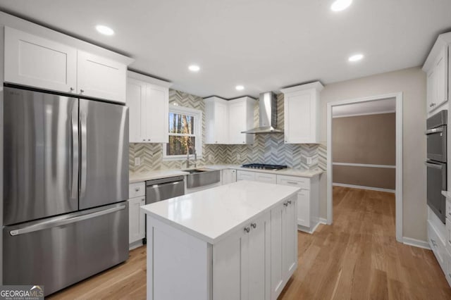 kitchen with a kitchen island, white cabinetry, appliances with stainless steel finishes, and wall chimney range hood