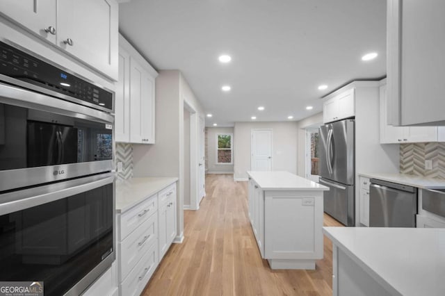 kitchen with white cabinetry, appliances with stainless steel finishes, a center island, and backsplash