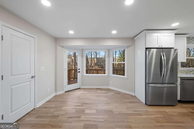 kitchen with stainless steel appliances, white cabinets, and light hardwood / wood-style flooring