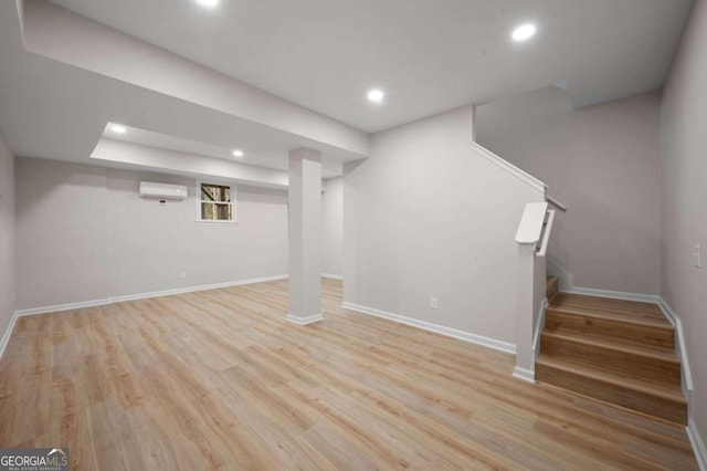 basement featuring light hardwood / wood-style floors and an AC wall unit