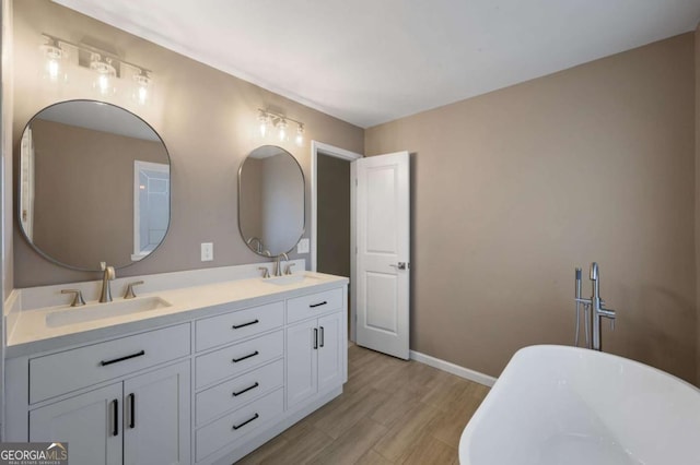 bathroom with a tub to relax in, hardwood / wood-style floors, and vanity