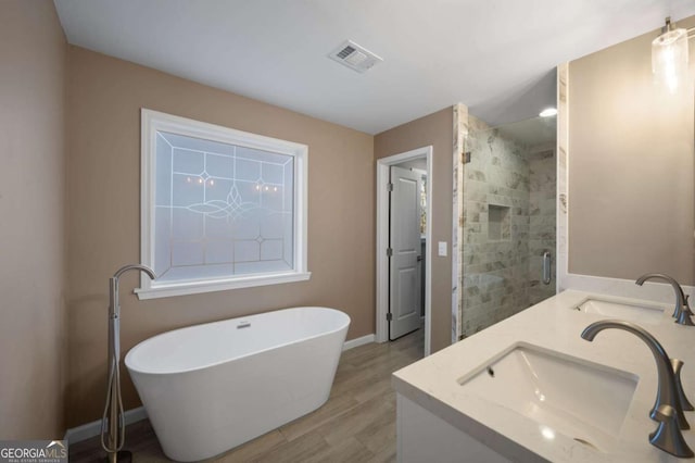 bathroom with hardwood / wood-style flooring, vanity, and plus walk in shower