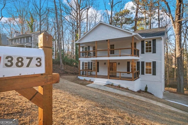 view of front facade featuring a front lawn, a balcony, and covered porch