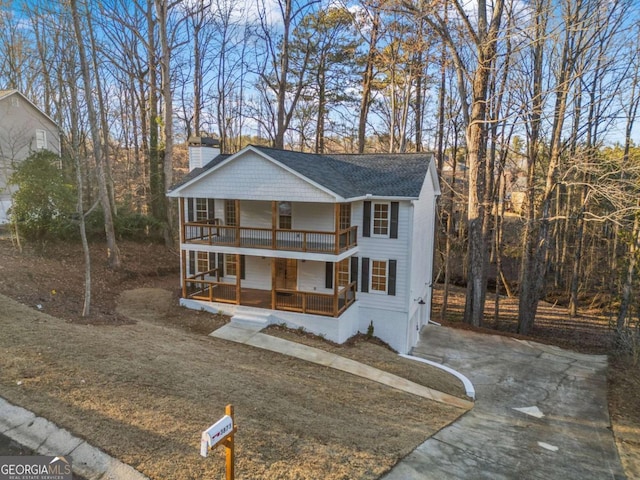 view of front of house with a front yard, a balcony, and a porch