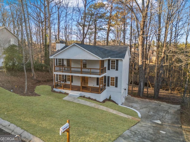 view of front of house featuring a front yard, a balcony, and covered porch