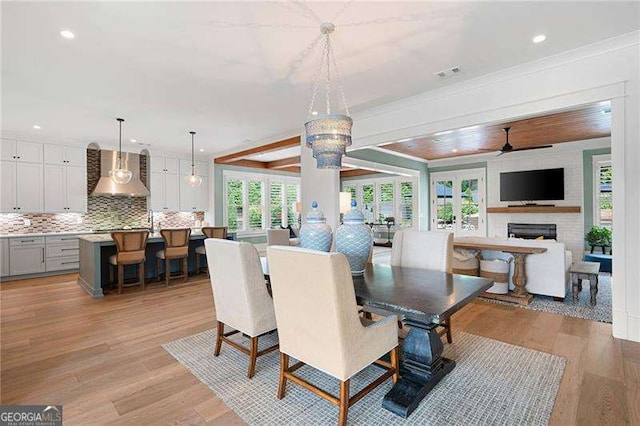 dining space featuring crown molding, a fireplace, and light wood-type flooring