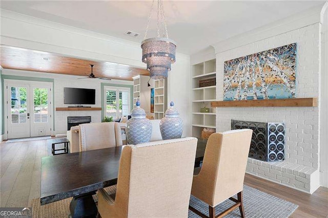 dining area featuring a brick fireplace, built in features, a wealth of natural light, and hardwood / wood-style floors