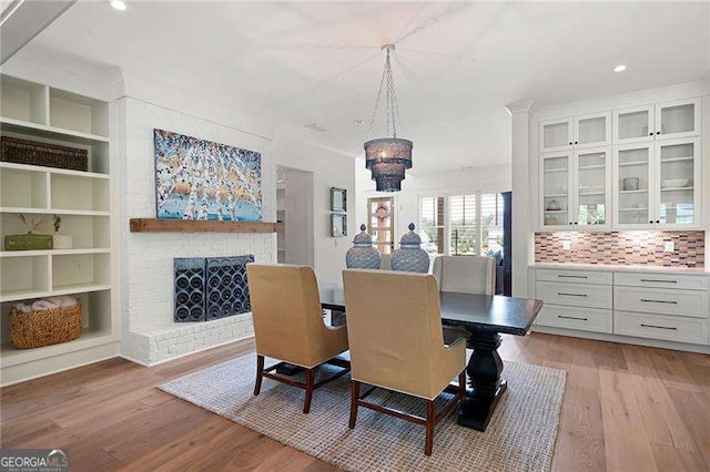 dining room featuring a fireplace, built in shelves, and light hardwood / wood-style flooring