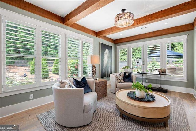 sunroom featuring a chandelier and beamed ceiling