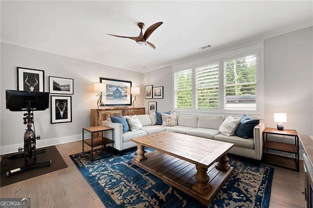 living room with crown molding, ceiling fan, and dark hardwood / wood-style floors