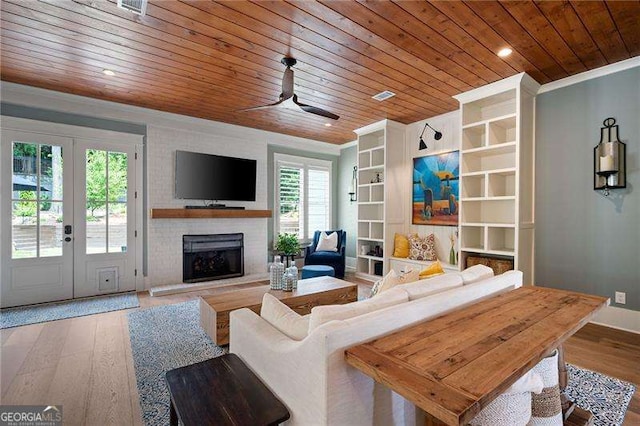 living room with hardwood / wood-style flooring, ornamental molding, a fireplace, and wooden ceiling