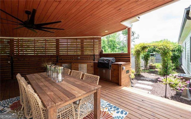 deck featuring grilling area, ceiling fan, and exterior kitchen