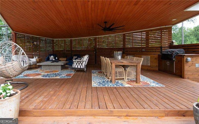 deck featuring exterior kitchen, area for grilling, an outdoor living space with a fire pit, and ceiling fan