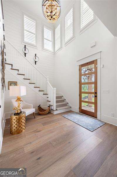 foyer entrance featuring a notable chandelier, hardwood / wood-style flooring, and a towering ceiling