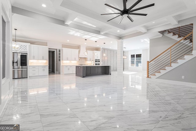 unfurnished living room with stairs, marble finish floor, ceiling fan with notable chandelier, and decorative columns