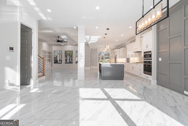 kitchen with marble finish floor, decorative columns, recessed lighting, open floor plan, and an island with sink