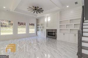 unfurnished living room with built in shelves and a tray ceiling