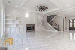 unfurnished living room featuring a tray ceiling, ornamental molding, built in features, and french doors