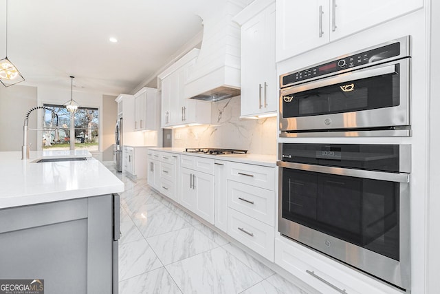 kitchen with premium range hood, a sink, marble finish floor, appliances with stainless steel finishes, and decorative backsplash