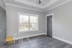 unfurnished bedroom featuring crown molding, dark hardwood / wood-style floors, and a tray ceiling