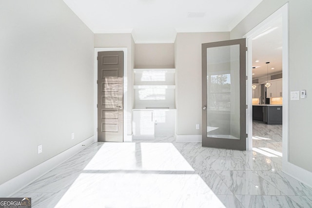 bedroom featuring ornamental molding, marble finish floor, ensuite bath, and baseboards