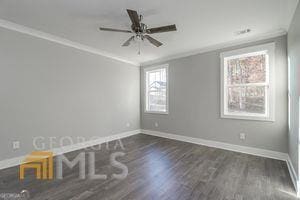 empty room with ornamental molding, dark hardwood / wood-style floors, and ceiling fan