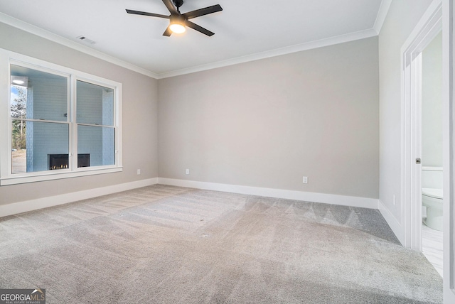 carpeted empty room with visible vents, crown molding, baseboards, and ceiling fan