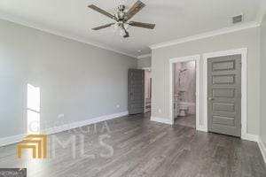 unfurnished bedroom featuring ornamental molding, dark hardwood / wood-style floors, and connected bathroom