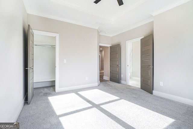 unfurnished bedroom with baseboards, a tray ceiling, carpet, and crown molding