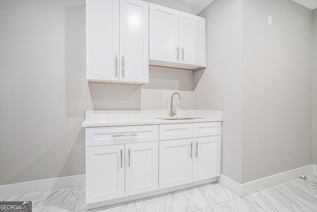 interior space featuring marble finish floor, baseboards, and a sink