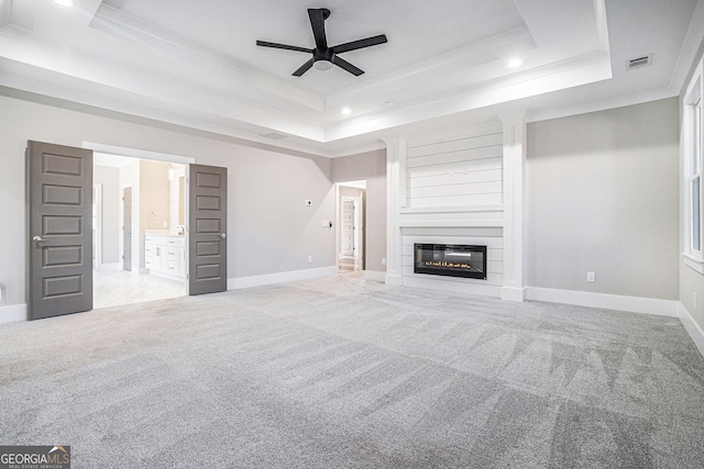 unfurnished living room featuring crown molding, a tray ceiling, and carpet flooring