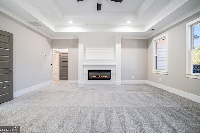 unfurnished living room with ornamental molding, carpet, and a raised ceiling