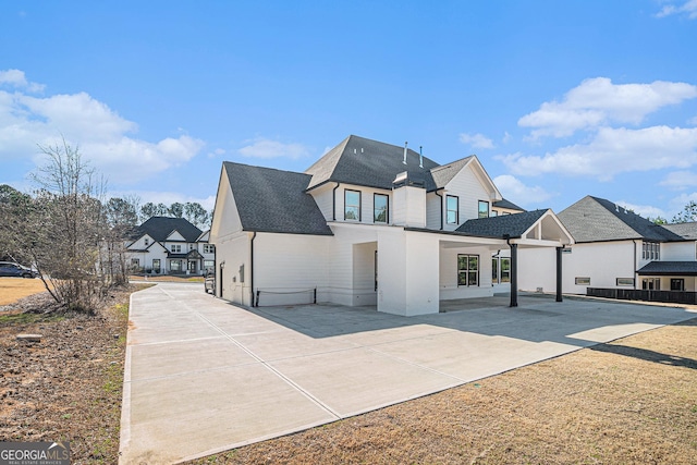 view of front of house with a patio area, a residential view, and roof with shingles