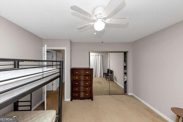 carpeted bedroom with ceiling fan, a closet, and a textured ceiling